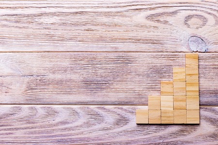 A wooden blocks cube over black wooden textured background with copy space for add word text title. Concept or conceptual Wood block stair or five steps. Cubic.の写真素材