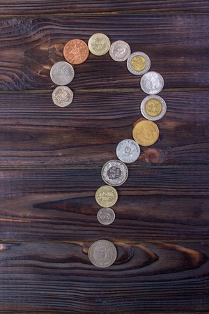 question mark from coins of different countries on a wooden backgroundの写真素材