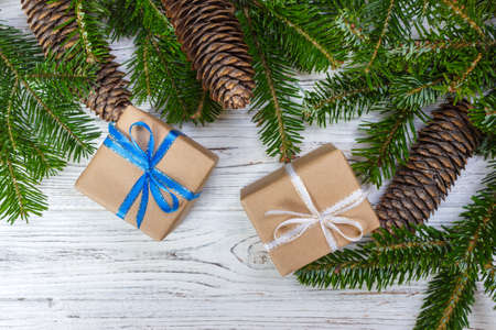 Christmas gift box on the white wooden table background,spruce branch,pine cones,frame,top view, space for text.の写真素材