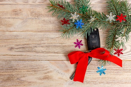 Close-up view of car keys with red bow as present on wooden background.の写真素材
