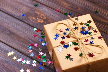 Gift box with star. Creative concept with festive decor on black background. Confetti stars, red,...