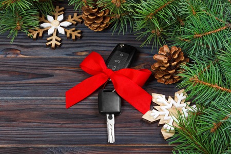 Close-up view of car keys with red bow as present on wooden background.の写真素材
