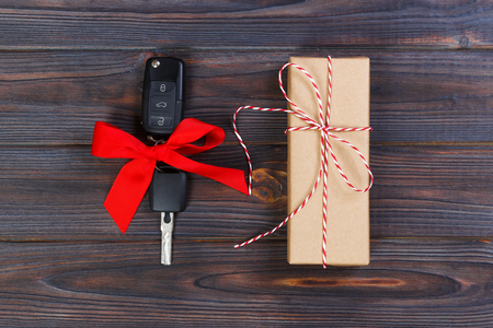 Close-up view of car keys with red bow as present on wooden background.の写真素材
