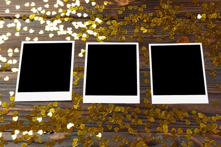 Blank instant photo and love gold confetti hearts on wooden table background.の写真素材