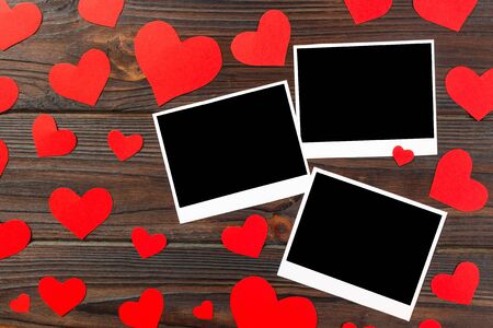 Instant photo with paper heart on old wooden background.