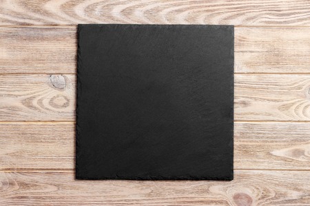 Slate board over old wooden background with copy space.の写真素材
