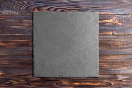 Slate blackboard on wooden table on wooden background.の写真素材