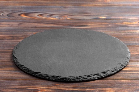 Slate plate on table. black slate stone on wooden background. copy space.の写真素材