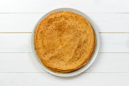 Stack of pancakes on white wooden table, top view.