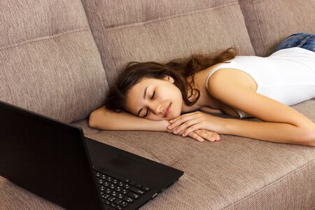 girl fell asleep with a laptop on the sofa .Tired and fell asleep.の写真素材