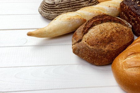 Assortment of baked bread on wooden table background.