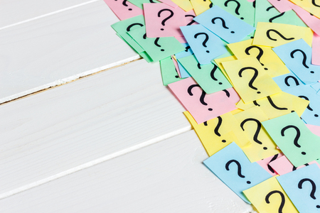 Just a lot of question marks on colored papers on wood background.