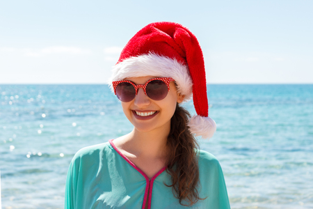 Woman in santa's hat in bikini at tropical beach. Christmas vacation.の写真素材