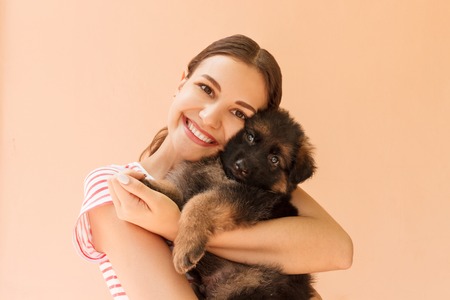 Young woman enjoys hugging a small cute puppy.の写真素材