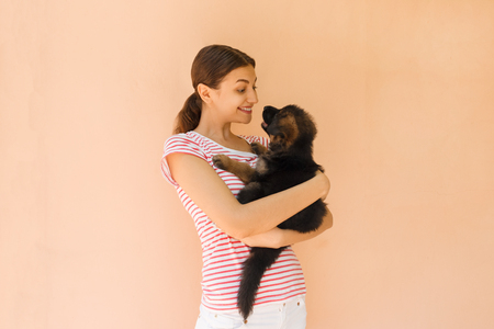 Young woman keeping black German shepherd puppy near her face.の写真素材