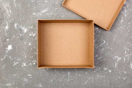 Empty opened brown cardboard box for mock up on gray cement table with copy space.