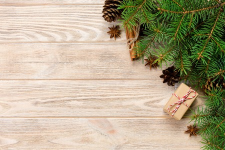 gift boxwith cinnamon sticks, anise stars, pine cones and pine branches on wooden table. Top view....