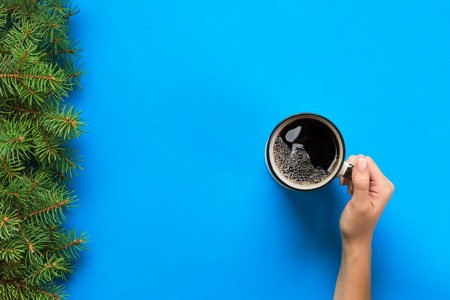 Minimalistic style woman hand holding a mug of coffee on background. Flat lay, top view.の写真素材