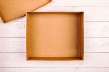 Opened empty cardboard box on wooden background. Top view vintage, toned.の写真素材