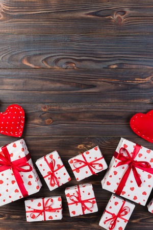 Valentine or other holiday handmade present in paper with red hearts and gifts box in holiday wrapper. Present box of gift on dark wooden table top view with copy space, empty space for design.の写真素材