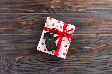 Valentine or other holiday handmade present in paper with red hearts, car keys and gifts box in holiday wrapper. box gift on Farkwooden table top view with copy space, empty space for design.の写真素材