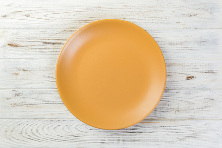 Directy above Empty yellow matte plate on white wooden background.の写真素材