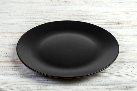 Perspective view. Empty black matte plate on white wooden background.の写真素材