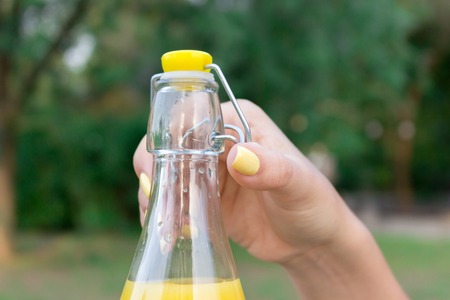 Cropped image of a woman while opening a cold bottle of lemonade in a hot day in the park.の写真素材