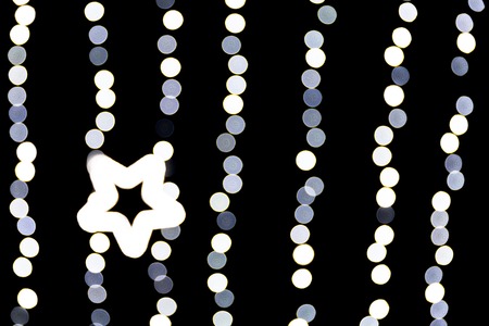 Abstract bokeh of white city lights on black background. defocused and blurred with star of light.の写真素材