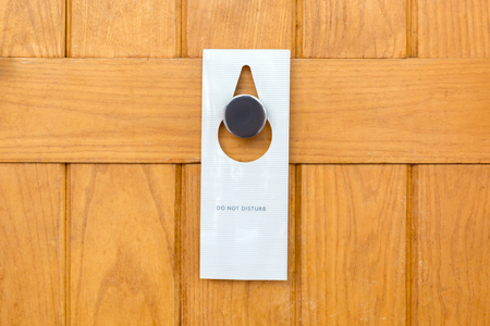 please do not disturb sign on Closed wooden door of hotel room.の写真素材
