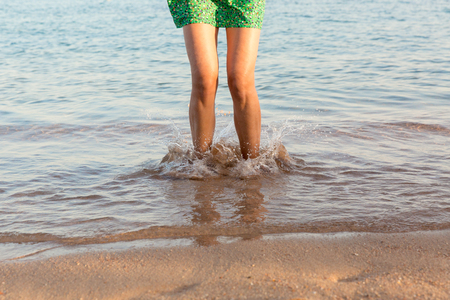 Leg of woman running on beach with water splashing. summer vacation. legs of a girl walking in water on sunset.の写真素材