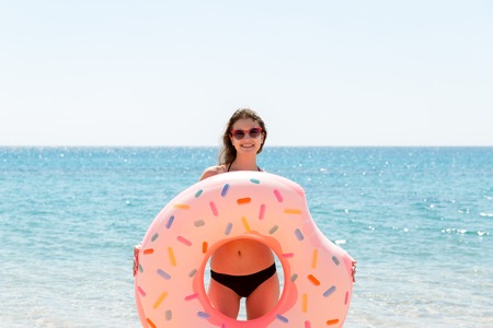 Beautiful crazy woman relaxing and playing with inflatable ring in sea beach. Summer holidays and vacation concept.の写真素材
