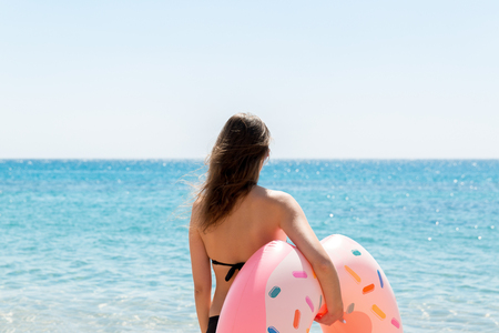A woman walks into the sea water. Girl relaxing on inflatable ring on the beach. Summer holidays and vacation concept.の写真素材