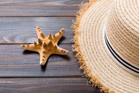 Straw hat and starfish On a dark wooden background. top view summer holiday concept with copy space.の写真素材