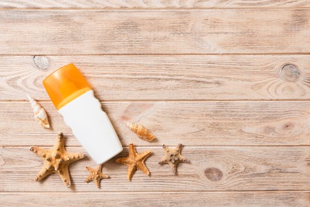sun protection cream bottle and seashells on wooden background with copy space. flat lay concept of summer travel vacation.の写真素材
