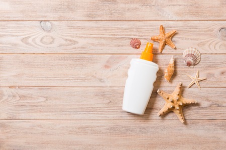 Top view of sunscreen bottle with starfish on wooden board background with copy space. flat lay...
