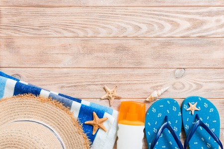 flip flops, straw hat, starfish, sunscreen bottle, body lotion spray on wooden background top view . flat lay summer beach sea accessories background, travel concept.の写真素材