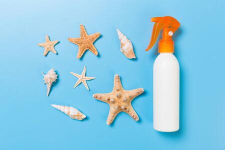 Sunscreen bottles with seashells on blue wooden table.の写真素材