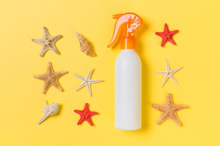 Sunscreen bottles with seashells on yellow wooden table.の写真素材