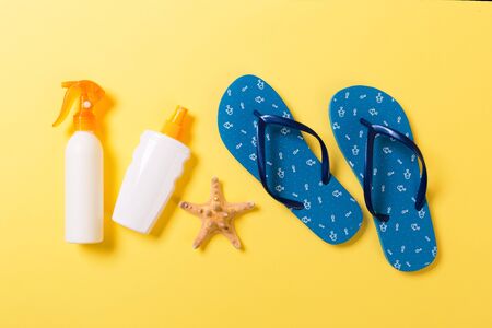 Sunscreen bottle or body spray on yellow background top view flat lay with copy space. Holiday...