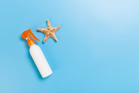 sunscreen cream with starfish and seashells in bottles on blue background, top view.の写真素材
