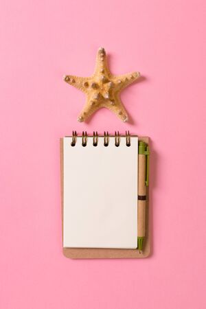 blank note book with starfish or seashells on a pink background , summer vaction concept.の写真素材