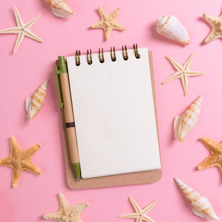 notebook with sseashells on pink background top view flat lay. Planning summer holidays, tourism and vacation concept.の写真素材
