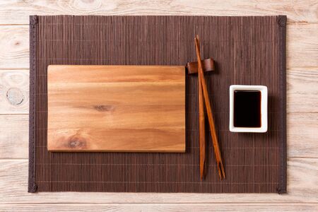 Empty rectangular wooden plate with chopsticks for sushi and soy sauce on wood background. Top view with copy space.の写真素材