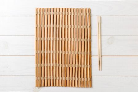 two sushi chopsticks with empty bamboo mat or wood plate on wooden Background Top view with copy stace.の写真素材