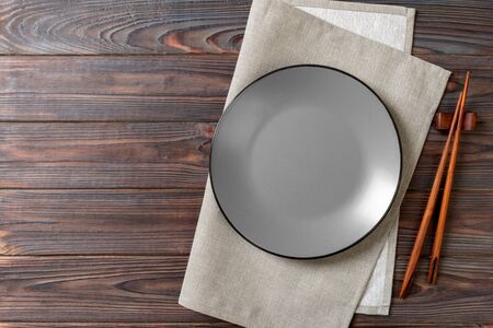 Empty grey round plate with chopsticks for sushi on wooden background. Top view with copy space.の写真素材
