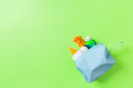 Top view of female cosmetics bag full of suncream spray, sunsreen, sunblock and body lotion and spf cream on green background with copy space. Directly above. Bright summer concept.の写真素材