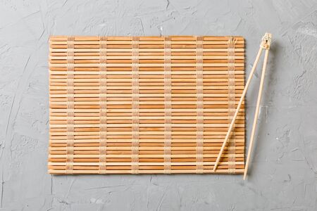 two sushi training sticks with empty bamboo mat or wood plate on stone Background Top view with copy stace.の写真素材