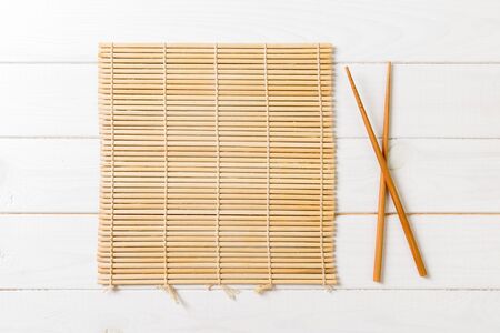 two sushi chopsticks with empty bamboo mat or wood plate on wooden Background Top view with copy stace.の写真素材