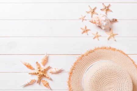 Summer holiday background with straw hat and seashells on wooden background top view with copy...